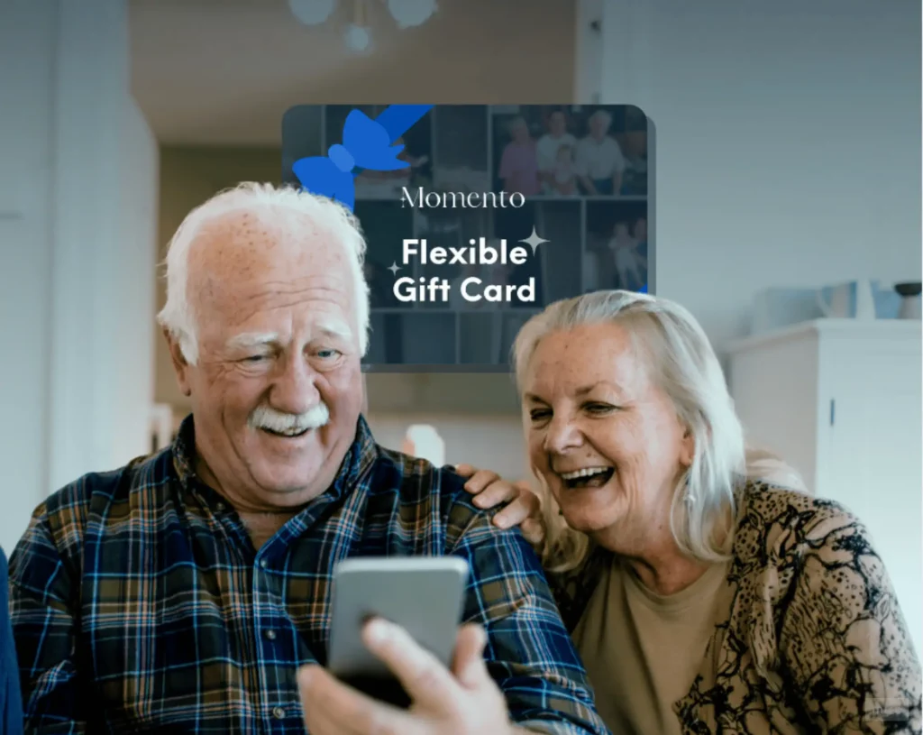 Elderly couple smiling while viewing digitised family photos on a smartphone, representing a Momento flexible gift card for photo digitisation.