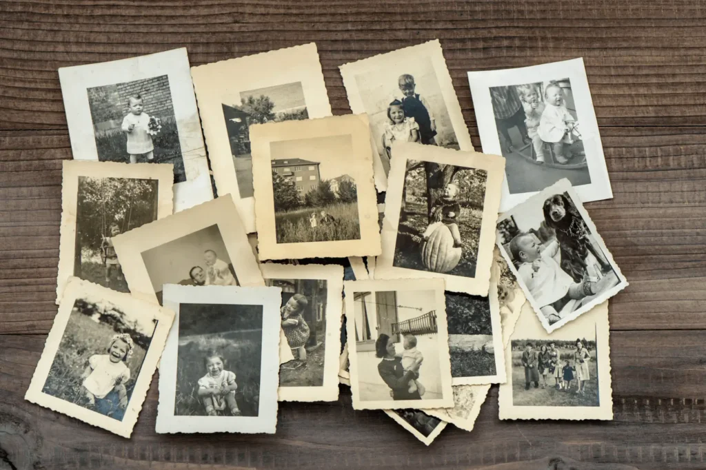 A collection of vintage family photographs scattered on a wooden table, ready to be digitised and preserved.